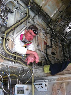 Jim Schmidgall is working on an Airbus A330-300, center dry bay fuel leak. He shows the flexibility required in this center wing box, accessed through the main landing gear areas. Photo courtesy of Scott Orloff. Jim Schmidgall is working on an Airbus A330-300, center dry bay fuel leak. He shows the flexibility required in this center wing box, accessed through the main landing gear areas. Photo courtesy of Scott Orloff.