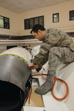Staff Sergeant Eric Hoff installs thrust reverser flange bolts. The fire sleeve is for a wiring harness to be installed later.
