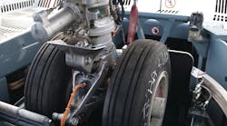 Two major components of the Taxibot make it different from other towbarless tractors: An interface mechanism clamps on the nose landing gear, which is in turn mounted on a “rotating turret.' Two major components of the Taxibot make it different from other towbarless tractors: An interface mechanism clamps on the nose landing gear, which is in turn mounted on a “rotating turret.'