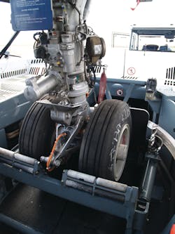 Two major components of the Taxibot make it different from other towbarless tractors: An interface mechanism clamps on the nose landing gear, which is in turn mounted on a “rotating turret.' Two major components of the Taxibot make it different from other towbarless tractors: An interface mechanism clamps on the nose landing gear, which is in turn mounted on a “rotating turret.'