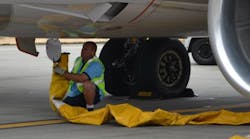 A worker attaches a hose to carry pre-conditioned air to a jet at Seattle-Tacoma International Airport on Aug. 13, 2013.