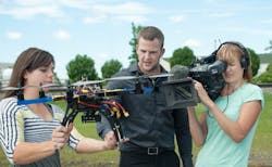 UND students Meagan Kaiser and Andrew Regenhard explain the operations of a small home-built UAS known as a &ldquo;hexapod&rdquo; while Marie Klar, a TV photographer with the Danish Broadcast Corp. looks on. Klar was part of a Danish news crew that visited the UND campus in late June 2013 to learn more about UAS operations taking place at UND&rsquo;s John D. Odegard School of Aerospace Sciences.