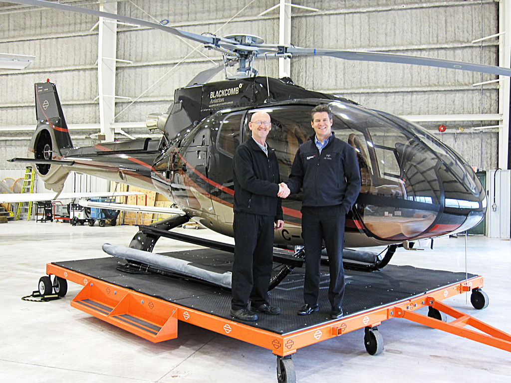 Vector's Regional Sales Director, Western Canada, Eric Hicks and Blackcomb's President and COO, Jonathan Burke shake hands in front of a Eurocopter EC130B4.