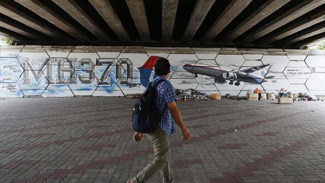 A man walks past graffiti depicting the missing Malaysia Airlines flight MH370 on the one year anniversary of its disappearance in Kuala Lumpur, on March 8, 2015.
