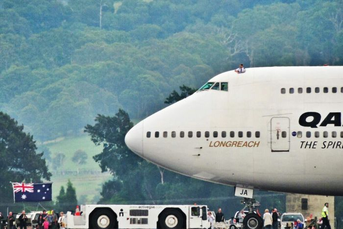 One of the pilots on the aircraft's final flight pokes his head out of the cockpit hatch after landing at Wollongong Airport.