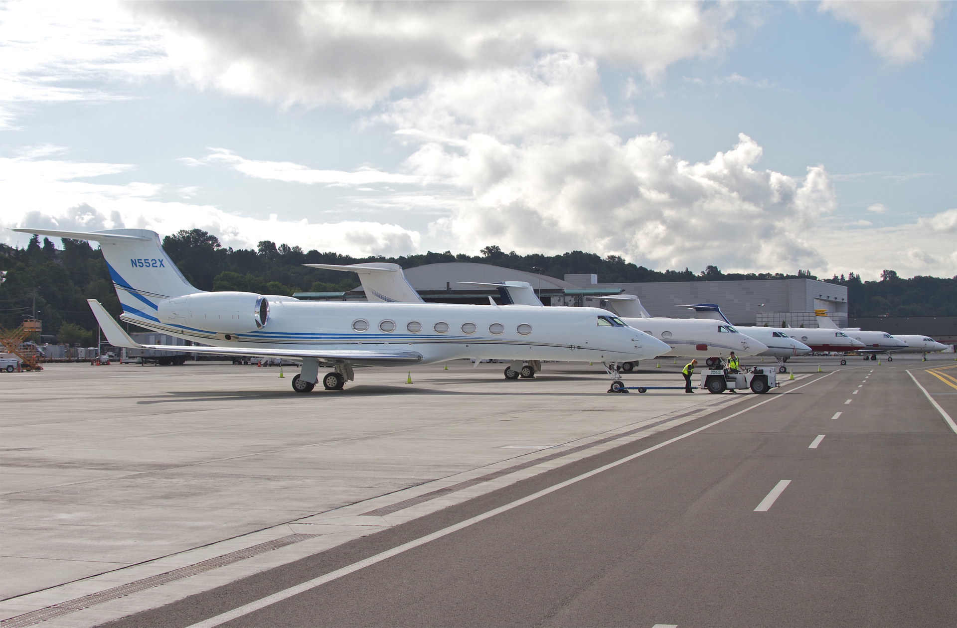Lined up for a morning departure at Boeing Field (KBFI) in 2013, a gaggle of Gulfstreams flanked by a lone Falcon 900 in the distance are positioned on the ramp adjacent the taxiway. Airside improvements such as hangars and FBO facilities are height limited to FAR 77 protected areas, thus situated behind the aircraft.