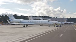 Lined up for a morning departure at Boeing Field (KBFI) in 2013, a gaggle of Gulfstreams flanked by a lone Falcon 900 in the distance are positioned on the ramp adjacent the taxiway. Airside improvements such as hangars and FBO facilities are height limited to FAR 77 protected areas, thus situated behind the aircraft.