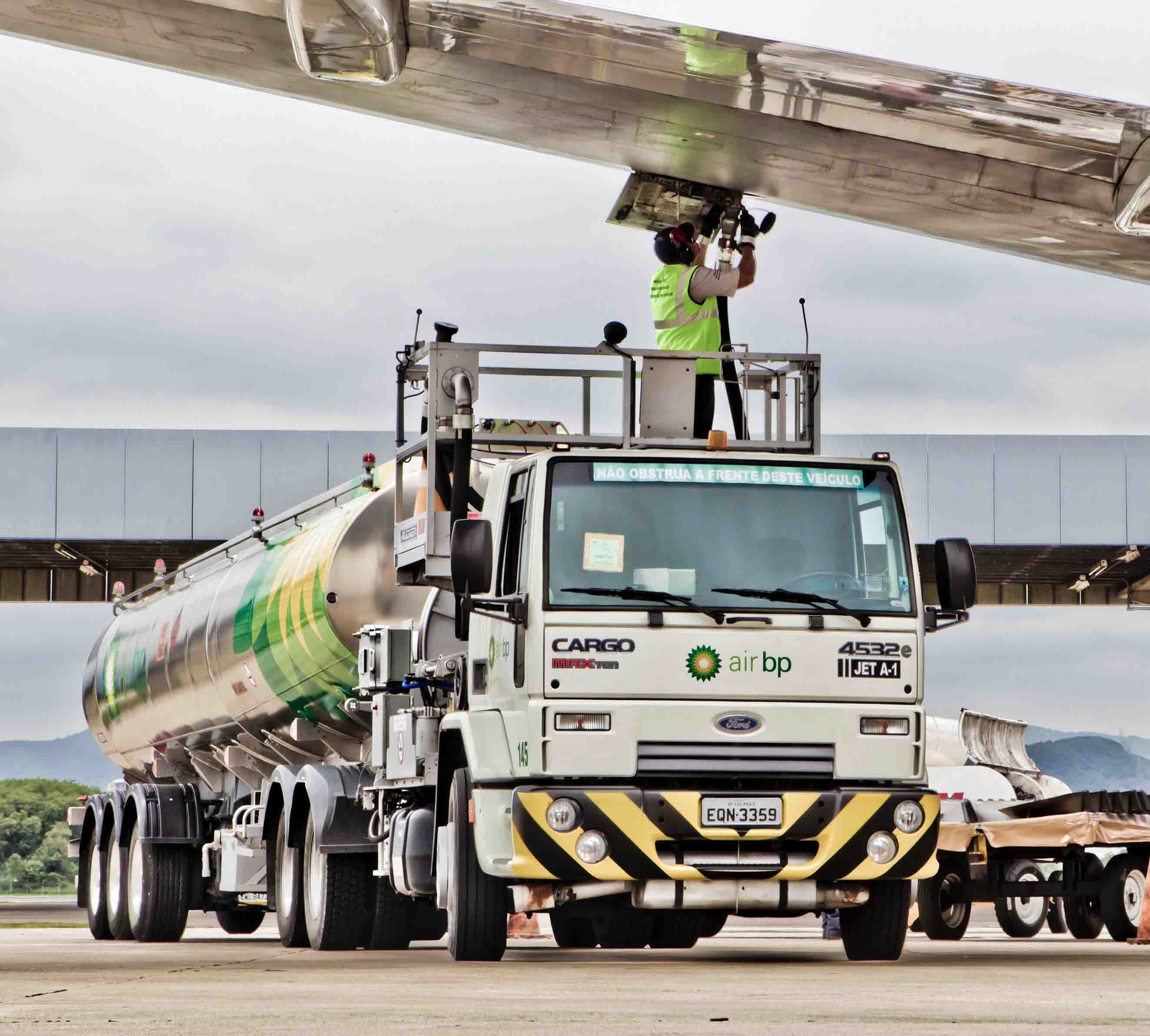 An Air BP tanker driver under the wing of an A320 aircraft at Galeao Airport in Rio de Janeiro, Brazil