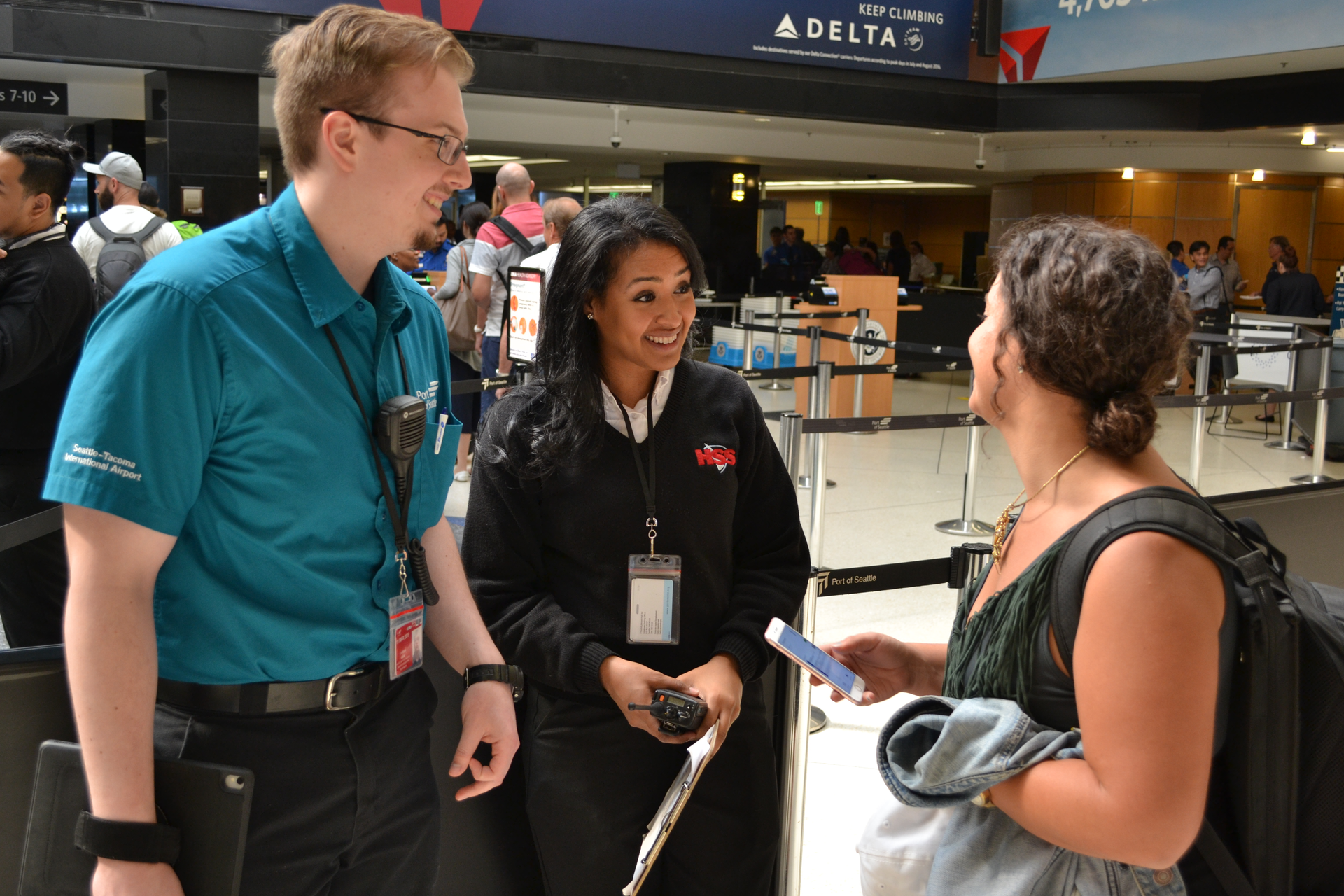 Sea-Tac Pathfinder, left, and customer service worker helping a traveler.