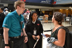 Sea-Tac Pathfinder, left, and customer service worker helping a traveler.