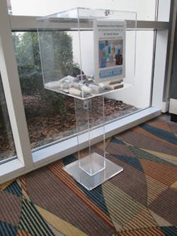 The airport helped get a secure box that would be appropriate for the waiting area near baggage claim. Passengers can drop items in the acrylic container on the way out the door. The airport helped get a secure box that would be appropriate for the waiting area near baggage claim. Passengers can drop items in the acrylic container on the way out the door.