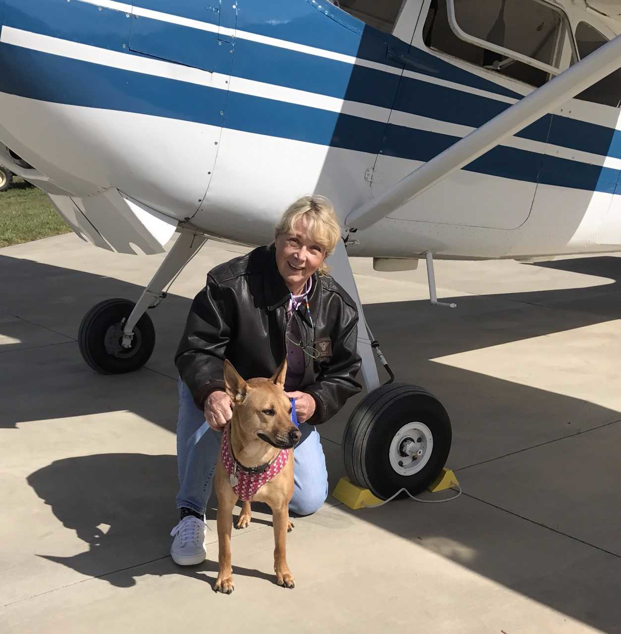 Susan Dusenbury with her dog, Taylor. That's her 1953 Cessna 180 in the background.