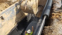 An initial layer of crushed stone bedding material was placed on top the geotextile, which was held in place on the side of the steel trench box with magnets. An initial layer of crushed stone bedding material was placed on top the geotextile, which was held in place on the side of the steel trench box with magnets.