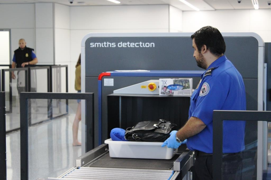 A TSA officer places a passenger's tray into the computed tomography (CT) scanner being tested in Terminal 1 at Los Angeles International Airport.