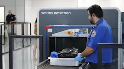 A TSA officer places a passenger's tray into the computed tomography (CT) scanner being tested in Terminal 1 at Los Angeles International Airport.