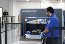 A TSA officer places a passenger&apos;s tray into the computed tomography (CT) scanner being tested in Terminal 1 at Los Angeles International Airport.