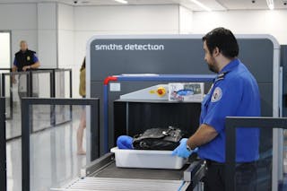 A TSA officer places a passenger&apos;s tray into the computed tomography (CT) scanner being tested in Terminal 1 at Los Angeles International Airport.