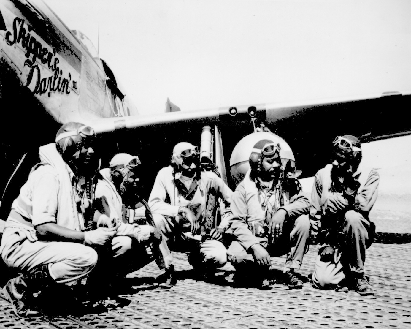 Fliers of a P-51 Mustang Group of the 15th Air Force in Italy `shoot the breeze' in the shadow of one of the Mustangs they fly. Left to right: Lt. Dempsey W. Morgan, Jr.; Lt. Carroll S. Woods; Lt. Robert H. Nelson, Jr.; Capt. Andrew D. Turner; and Lt. Clarence P. Lester.