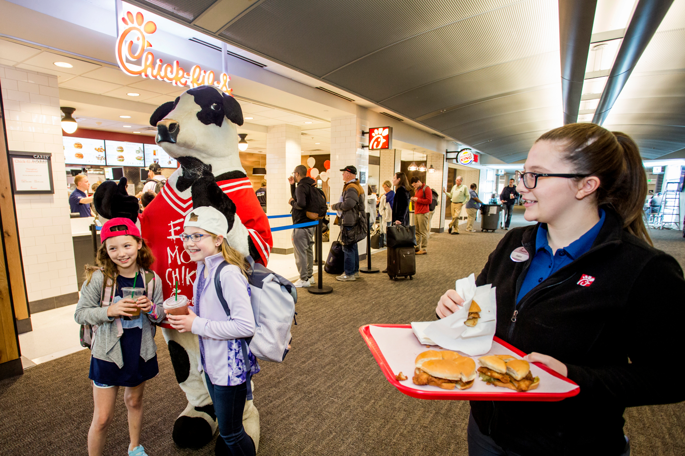 Chick-fil-A&rsquo;s famous cow kicks off Clinton National Airport opening, encouraging guests to 'EAT MOR CHIKIN' with signature chicken sandwich samples. )