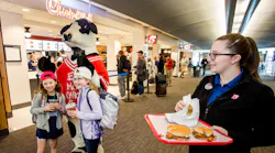 Chick-fil-A’s famous cow kicks off Clinton National Airport opening, encouraging guests to 'EAT MOR CHIKIN' with signature chicken sandwich samples. )