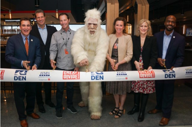 A ribbon cutting celebrates the grand opening of Great Divide Brewhouse and Kitchen at Denver International Airport. Pictured from left to right: HMSHost Vice President of Business Development Stephen Douglas; HMSHost President and CEO Steve Johnson; Great Divide Brewing Co. Founder Brian Dunn; Great Divide&rsquo;s Yeti; Colleen Forst; Denver International Airport CEO Kim Day; and Denver City Councilman Christopher Herndon.