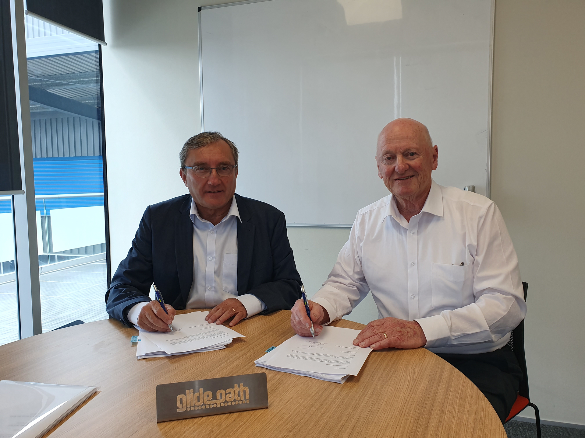 B2A Technology President Pierre Marol (l) and Glidepath Executive Chairman, Sir Ken Stevens (r) sign the agreement.