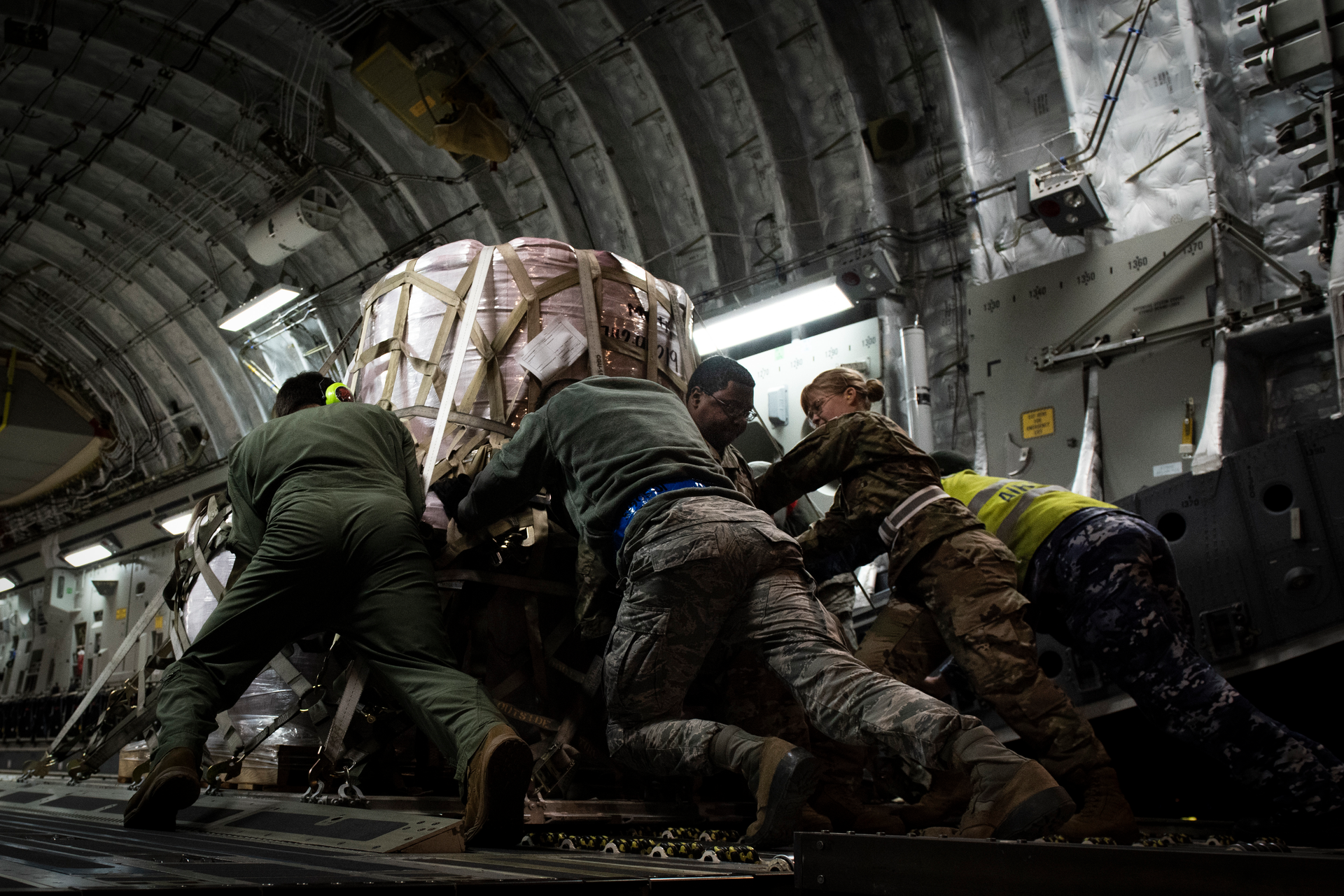 Members of the 99th Logistics Readiness Squadron and the Royal Australian Air Force push a pallet of fire suppressant up the ramp of an Australian C-17 Globemaster III, Jan. 16, 2020 at Nellis Air Force Base, Nev. Airmen from the United States and Australian Air Forces worked together to load the aircraft with the cargo to be delivered to Australia for aid in wildfire relief.