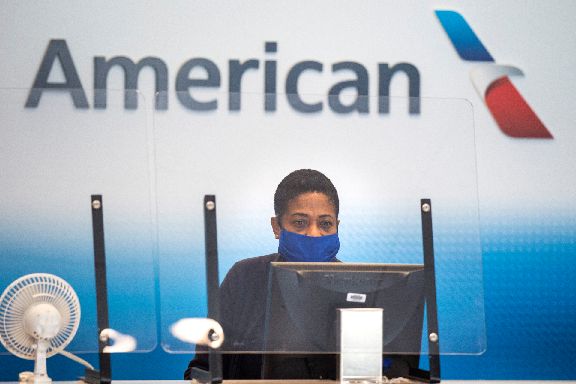 An American Airlines employee waits to help a passenger check luggage in Terminal A at DFW International Airport.
