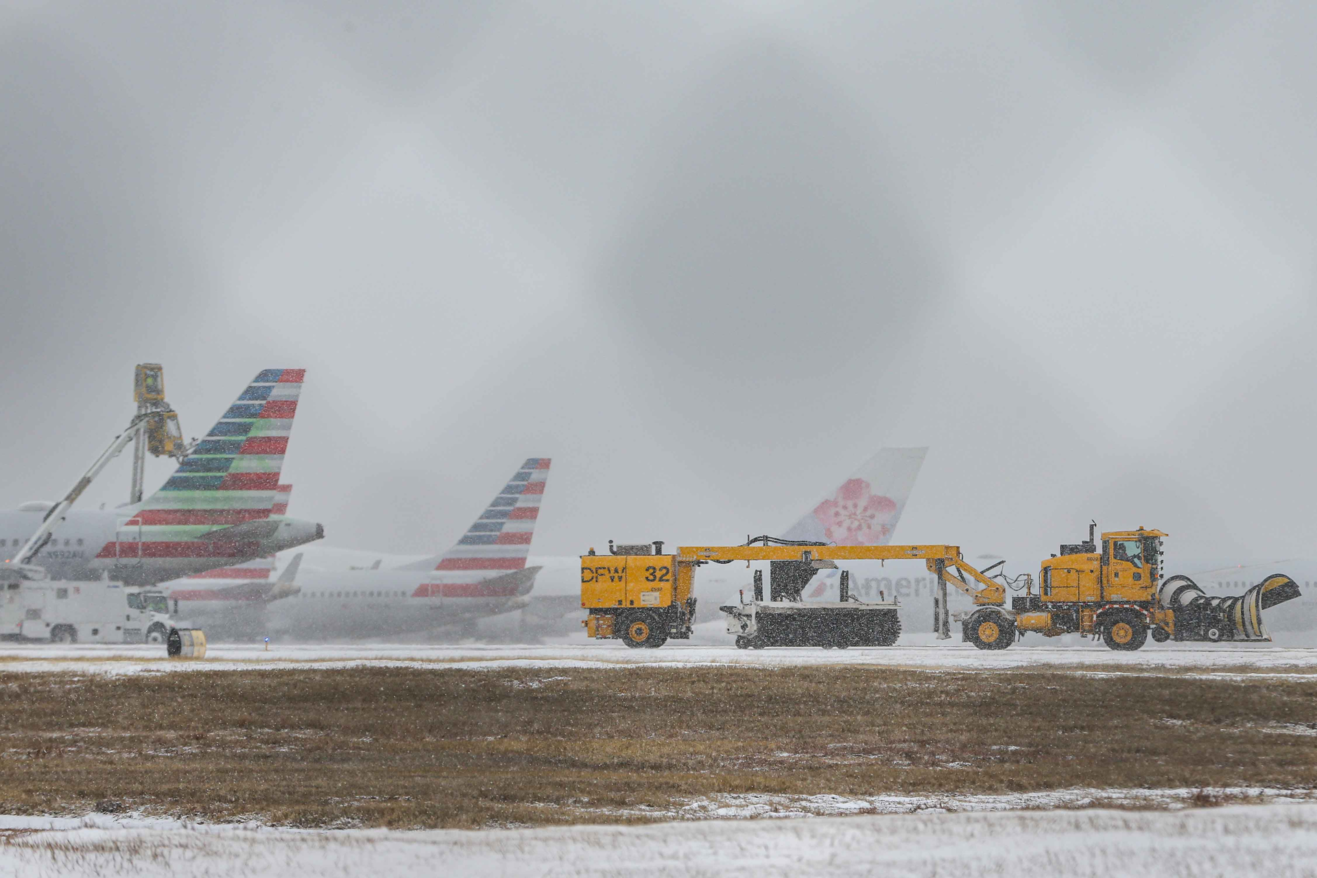 An American Airlines jets get inline to be de-iced at DFW International Airport before takeoff as winter flurries arrive in Irving on Sunday, February 14, 2021 ahead of major snowstorm.