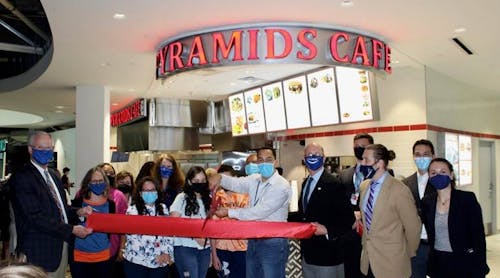 From left to right, Nashville International Airport President and CEO Doug Kreulen and Mike Mullaney, president and CEO of Fraport USA, hold the big red ribbon for George Hanna, surrounded by his family to celebrate the opening of Pyramids Caf&eacute; at BNA. Beloved in Nashville, Mr. Hanna&rsquo;s first airport location in Concourse C is now serving fliers fresh Mediterranean and Greek dishes.