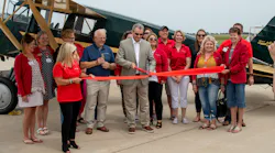 Guy Lieser, center, with Peter Limberger, left, cut the ribbon on the Janesville Jet Center in front of the 1929 Travel Air Model 10-D airplane.