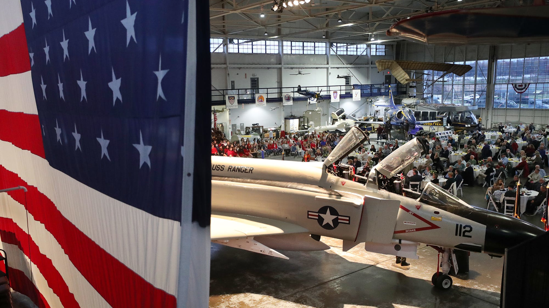 The F-4 Phantom is displayed in front of a large flag as more than 250 people attend the Veterans Day Celebration on Saturday at the MAPS Air Museum.