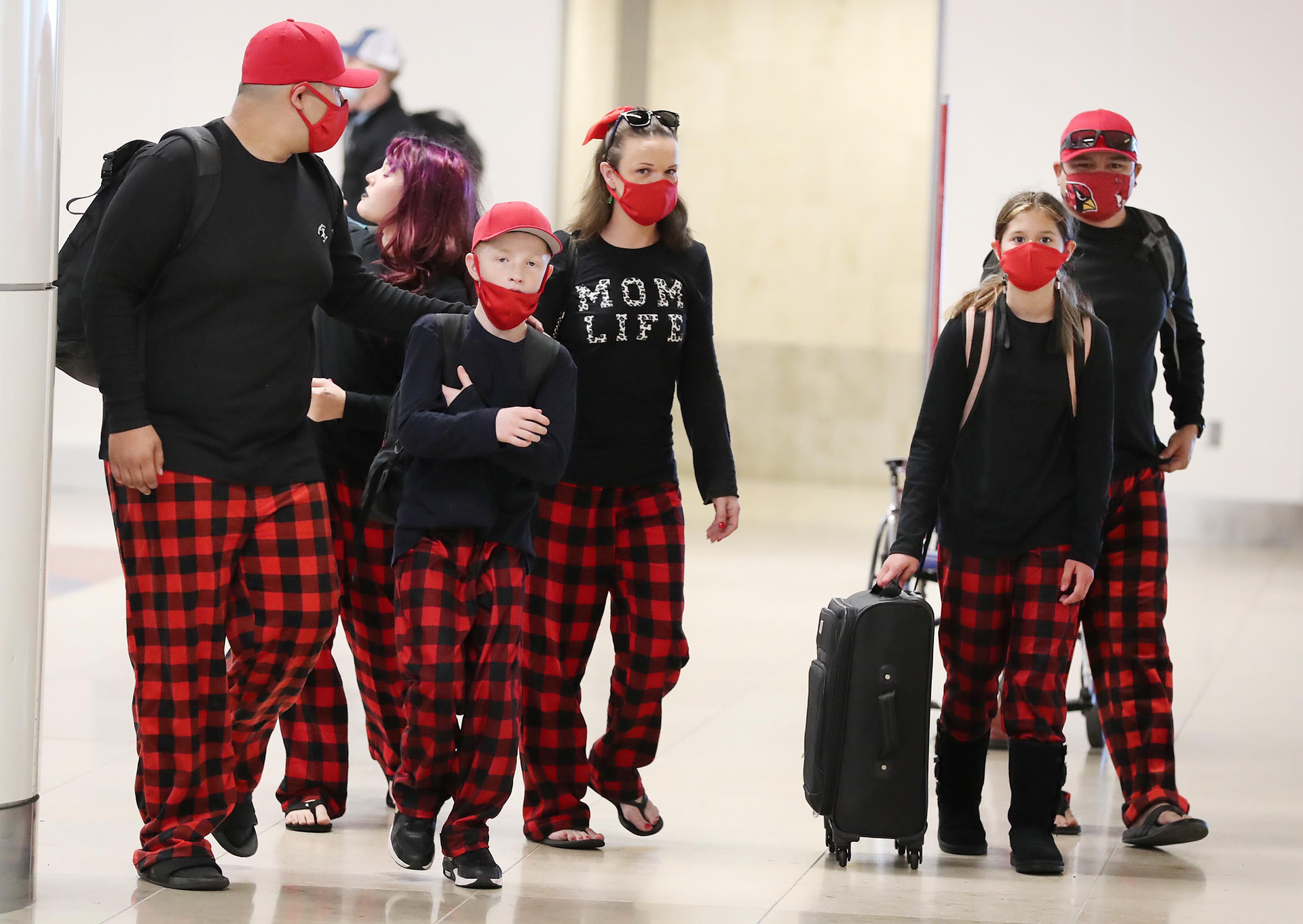 A family wearing matching pajama bottoms walks through Terminal A at Orlando International Airport on Christmas Day, Saturday, December 25, 2021. The family was catching a flight to Arizona.