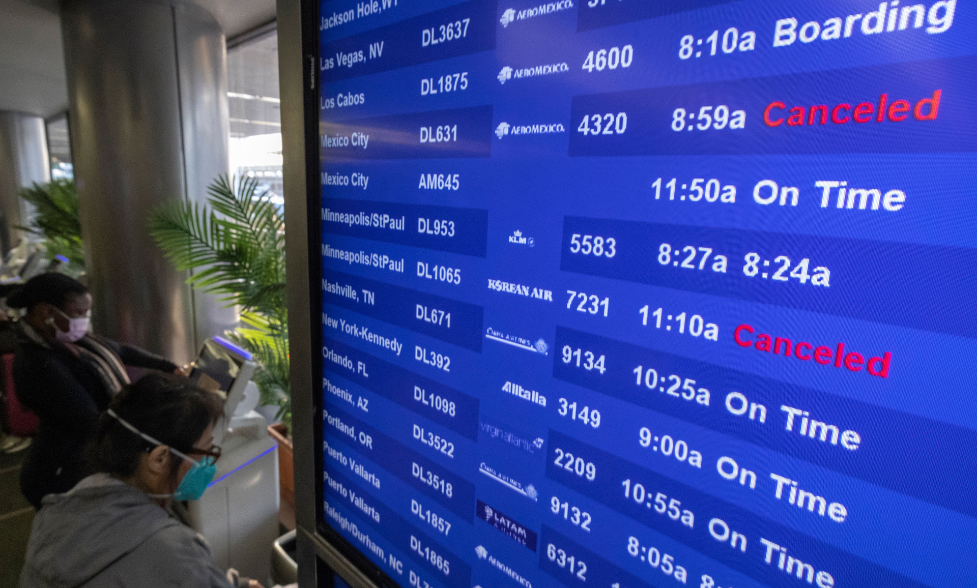 Travelers check for flight information at Los Angeles International Airport in Los Angeles on Dec. 24, 2021.