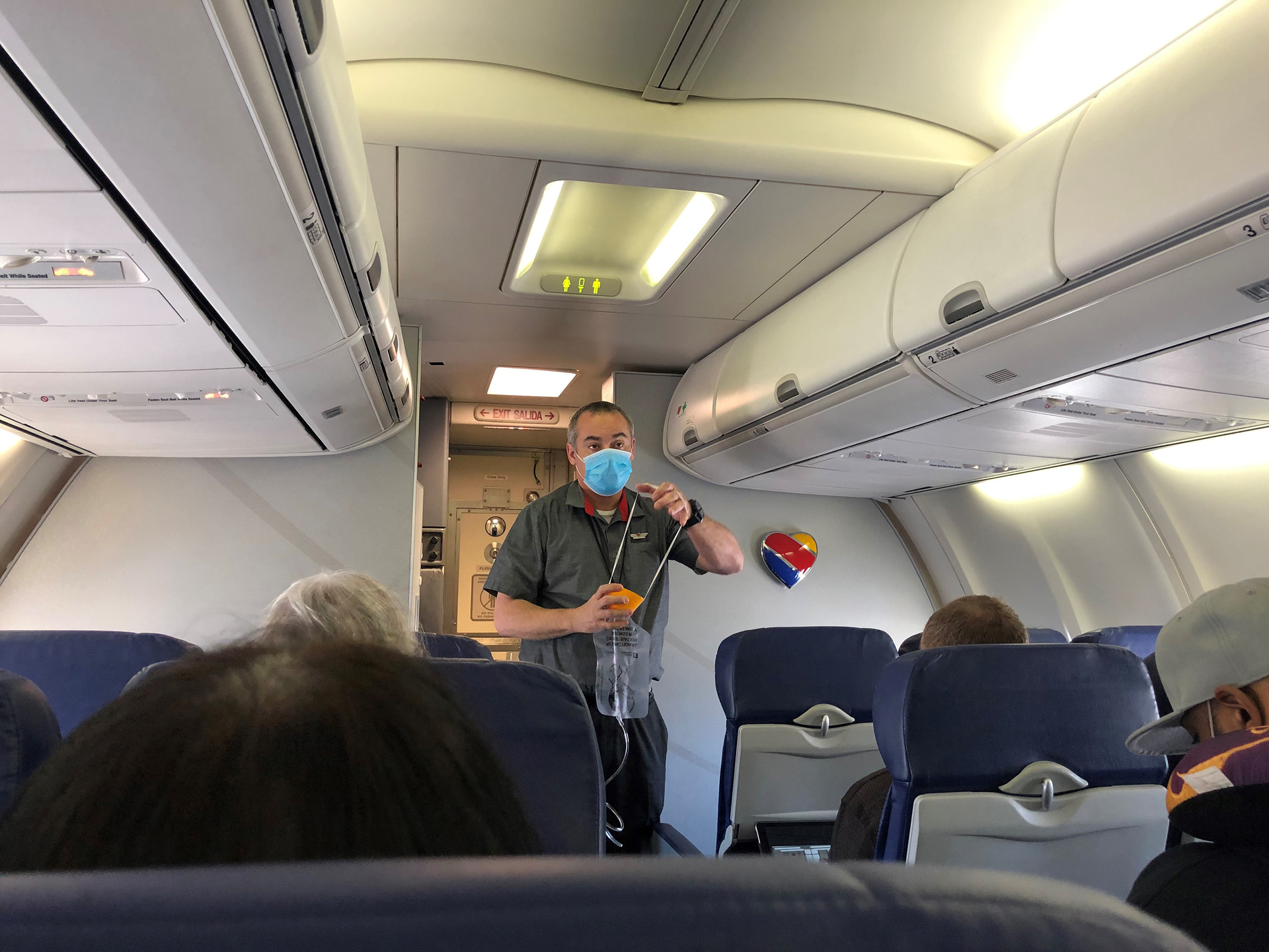 A Southwest Airlines flight attendant, wearing one mask, demonstrates the use of an oxygen mask at the outset of flight from Burbank, California, to Las Vegas in June 2021.