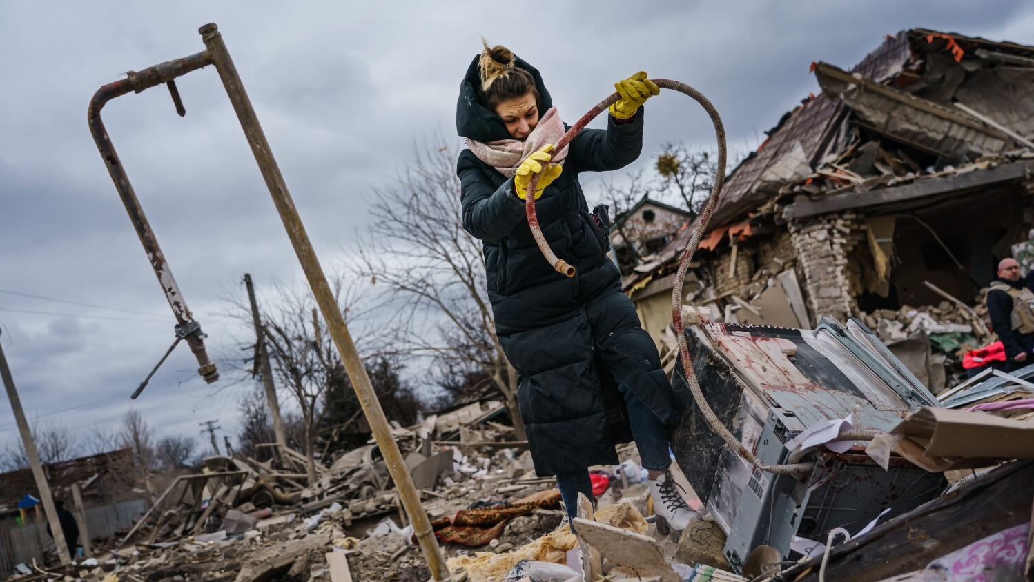 Residents help clear the rubble, sometimes covered in red stains, at a site of a home that was destroyed by a suspected Russian airstrike that killed at least six people in Markhalivka, Ukraine, on Saturday.