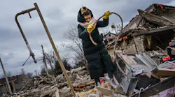 Residents help clear the rubble, sometimes covered in red stains, at a site of a home that was destroyed by a suspected Russian airstrike that killed at least six people in Markhalivka, Ukraine, on Saturday.