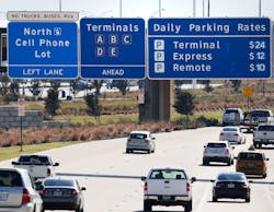 Road signs on Highway 114 inform drivers where the cellphone lot is located before the northbound entrance to DFW International Airport on Nov. 10, 2017. This will allow people to park and wait near the entrance of the airport without incurring parking fees.