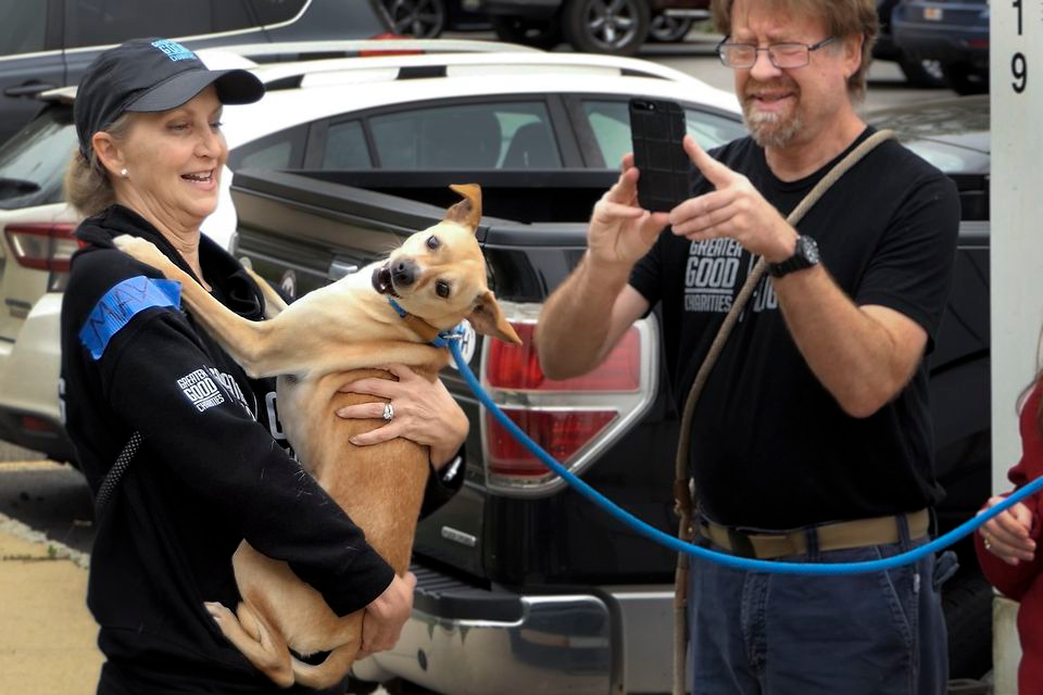 Erin Robbins, left, VP of Pet Programs for Greater Good Charities holds Max at St. Hubert's after the ride from the airport. St Hubert's volunteer Mark Lovretin, right, gets a photo.