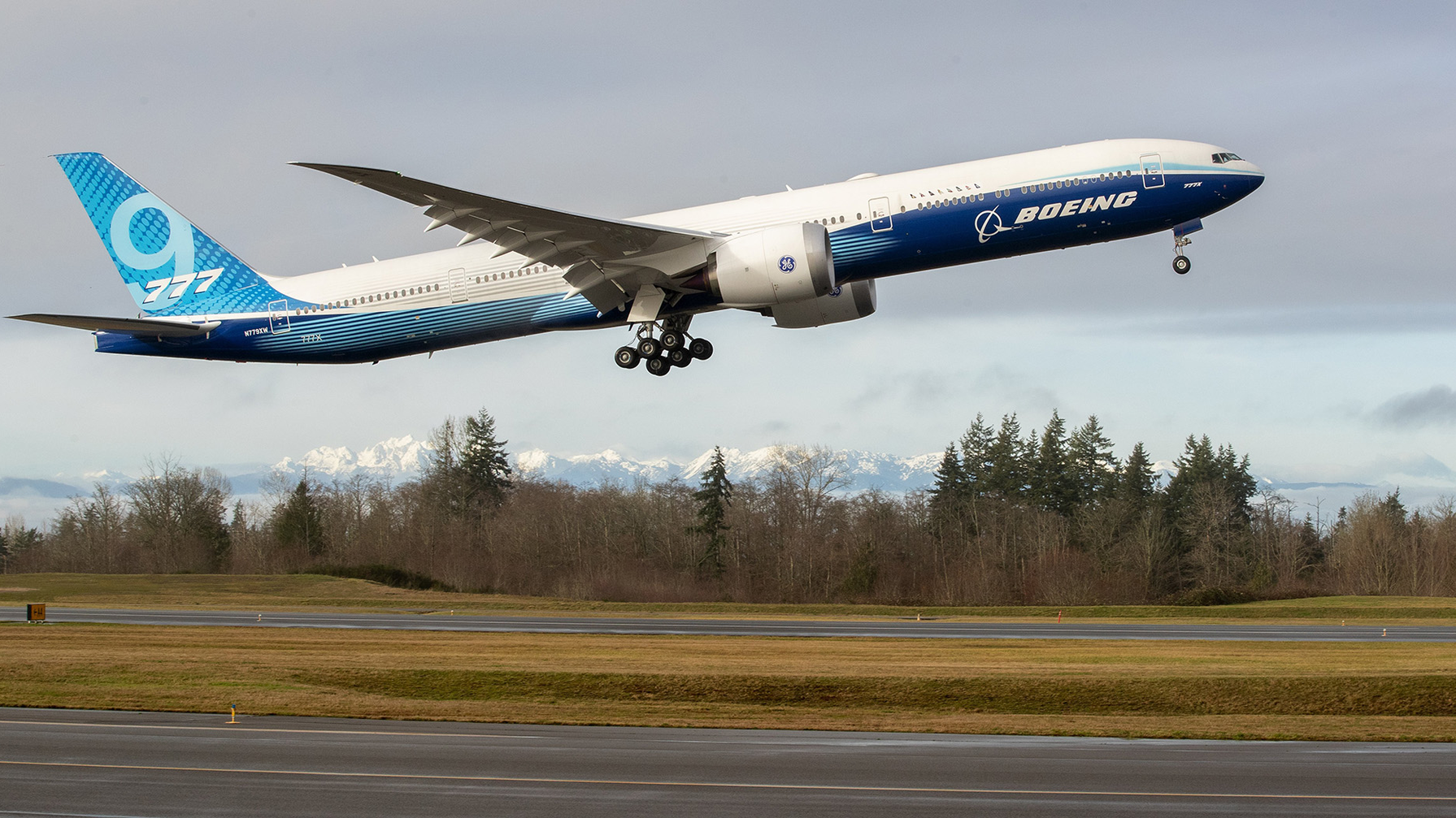 As the Olympic Mountains loom in the distance, the Boeing 777X takes off on its inaugural flight from Paine Field in Everett, Wash., on Saturday, Jan. 25, 2020. The 777X features giant carbon-composite wings, the largest Boeing has ever designed. The wings are so long that to fit at standard airport gates, each has to fold upward on a hinge 11 feet from the tip.