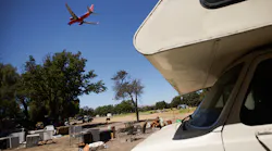 An airplane flies over the homeless encampment located along Coleman Avenue in San Jose, Calif., on Monday, June 28, 2021.