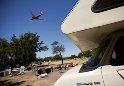 An airplane flies over the homeless encampment located along Coleman Avenue in San Jose, Calif., on Monday, June 28, 2021.
