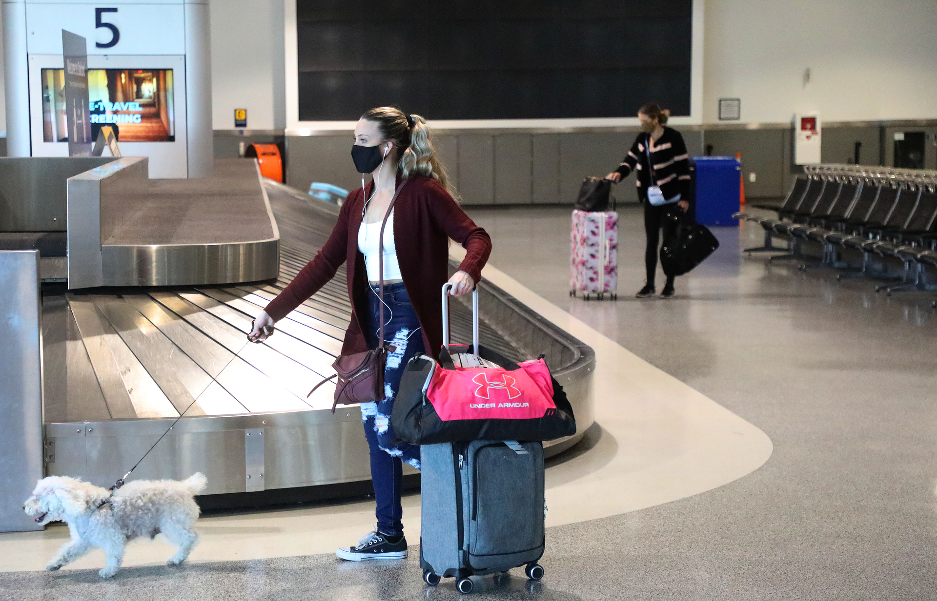 Travelers are photographed at the baggage claim area in Terminal 2 of the Oakland International Airport on Tuesday, Dec. 22, 2020, in Oakland, Calif.