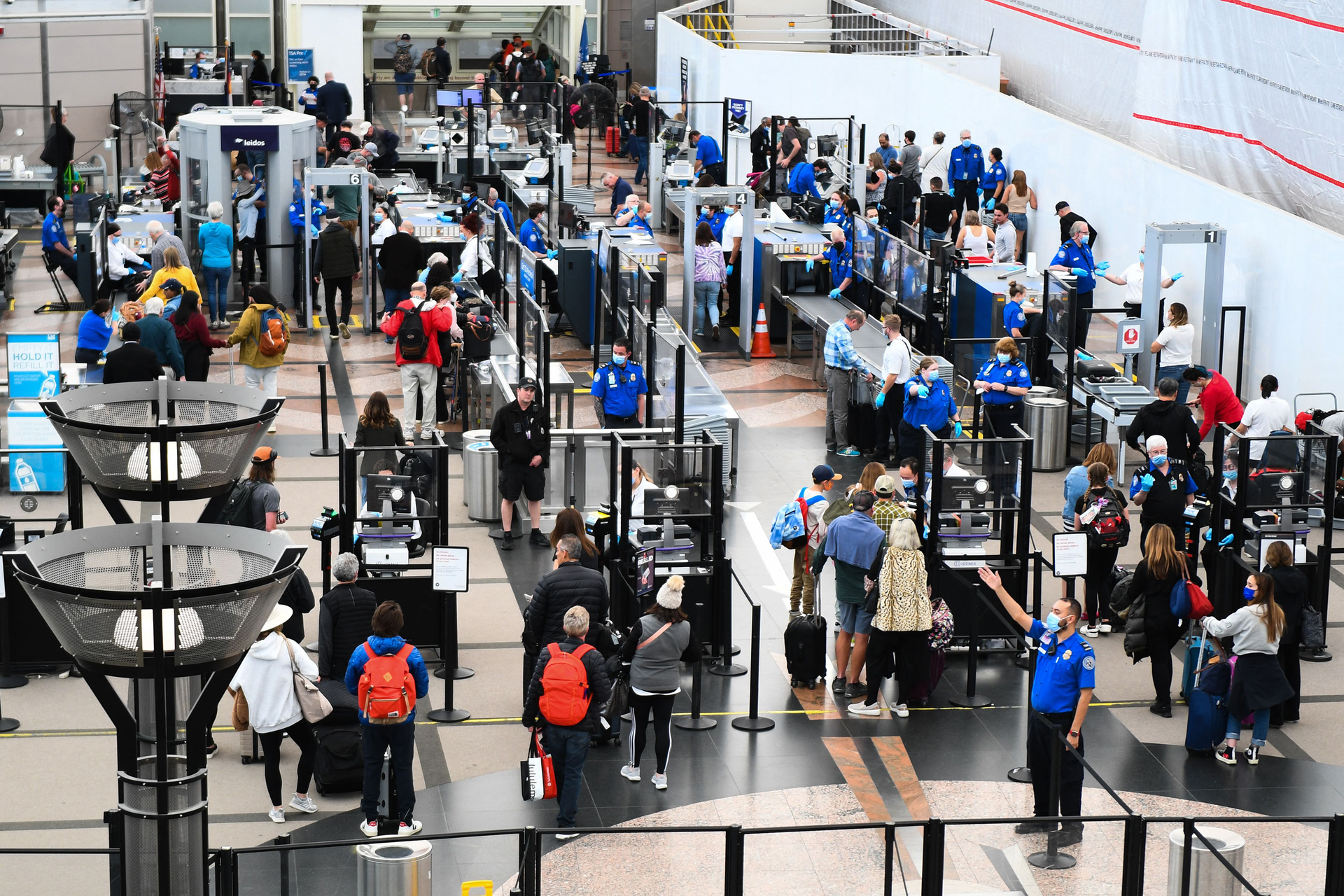 Airline passengers, some not wearing face masks following the end of COVID-19 public transportation rules, wait at a Transportation Security Administration (TSA) checkpoint to clear security before boarding to flights in the airport terminal in Denver on April 19, 2022.
