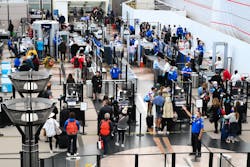 Airline passengers, some not wearing face masks following the end of COVID-19 public transportation rules, wait at a Transportation Security Administration (TSA) checkpoint to clear security before boarding to flights in the airport terminal in Denver on April 19, 2022.