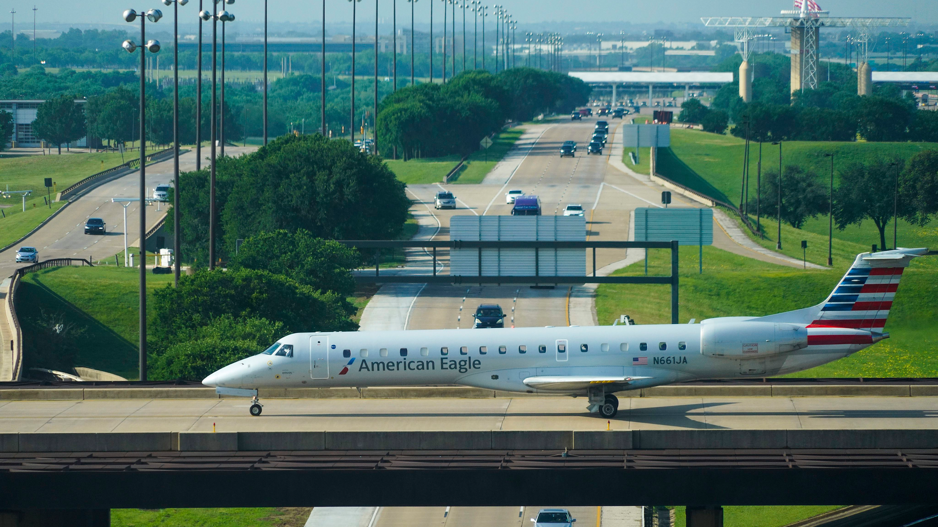 An American Eagle plane taxis on a bridge over International Parkway at DFW Airport on in May.