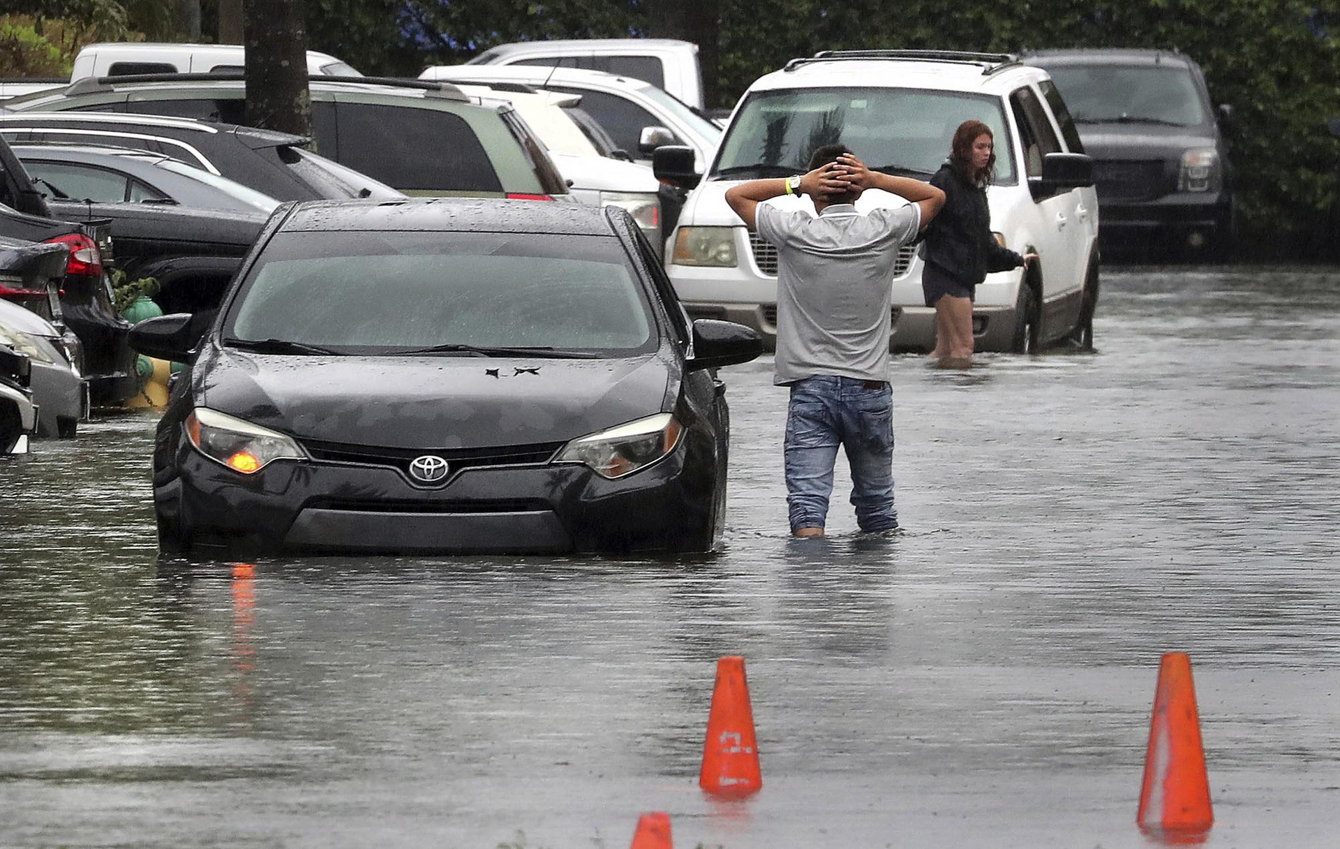 A driver climbs out of his stalled car after he tried to move it to higher ground in the parking lot at the Beachwallk at Sheridan Apartments in Dania Beach, Florida, on Saturday, June 4, 2022, as rains from the storm forecast to become Tropical Storm Alex cause flooding throughout South Florida.