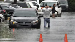 A driver climbs out of his stalled car after he tried to move it to higher ground in the parking lot at the Beachwallk at Sheridan Apartments in Dania Beach, Florida, on Saturday, June 4, 2022, as rains from the storm forecast to become Tropical Storm Alex cause flooding throughout South Florida.
