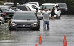 A driver climbs out of his stalled car after he tried to move it to higher ground in the parking lot at the Beachwallk at Sheridan Apartments in Dania Beach, Florida, on Saturday, June 4, 2022, as rains from the storm forecast to become Tropical Storm Alex cause flooding throughout South Florida.