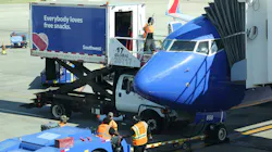 Airport workers wait on the tarmac as people board a plane to Washington, D.C., on July 1 at Dallas Love Field Airport.